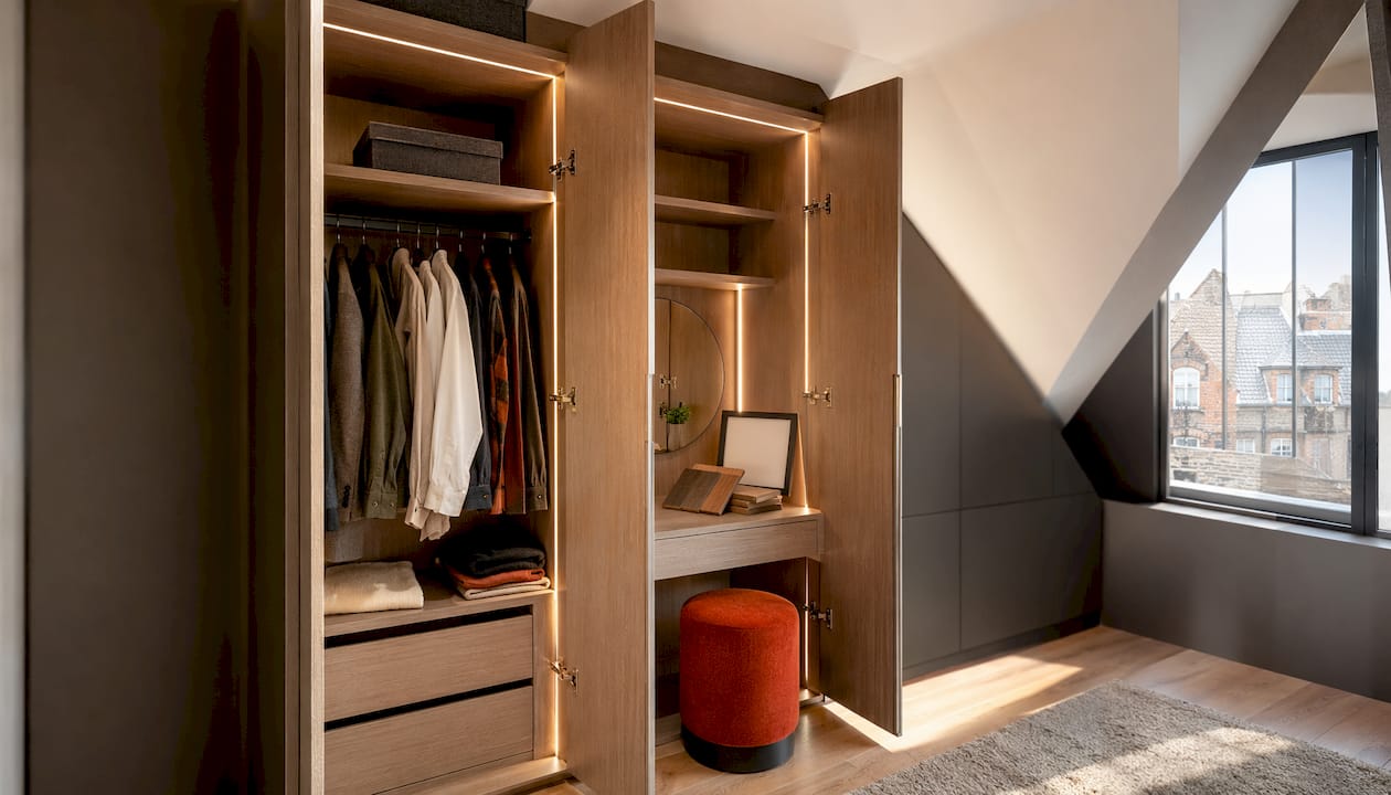 Interior of bespoke loft wardrobe with bamboo shelves and dressing table