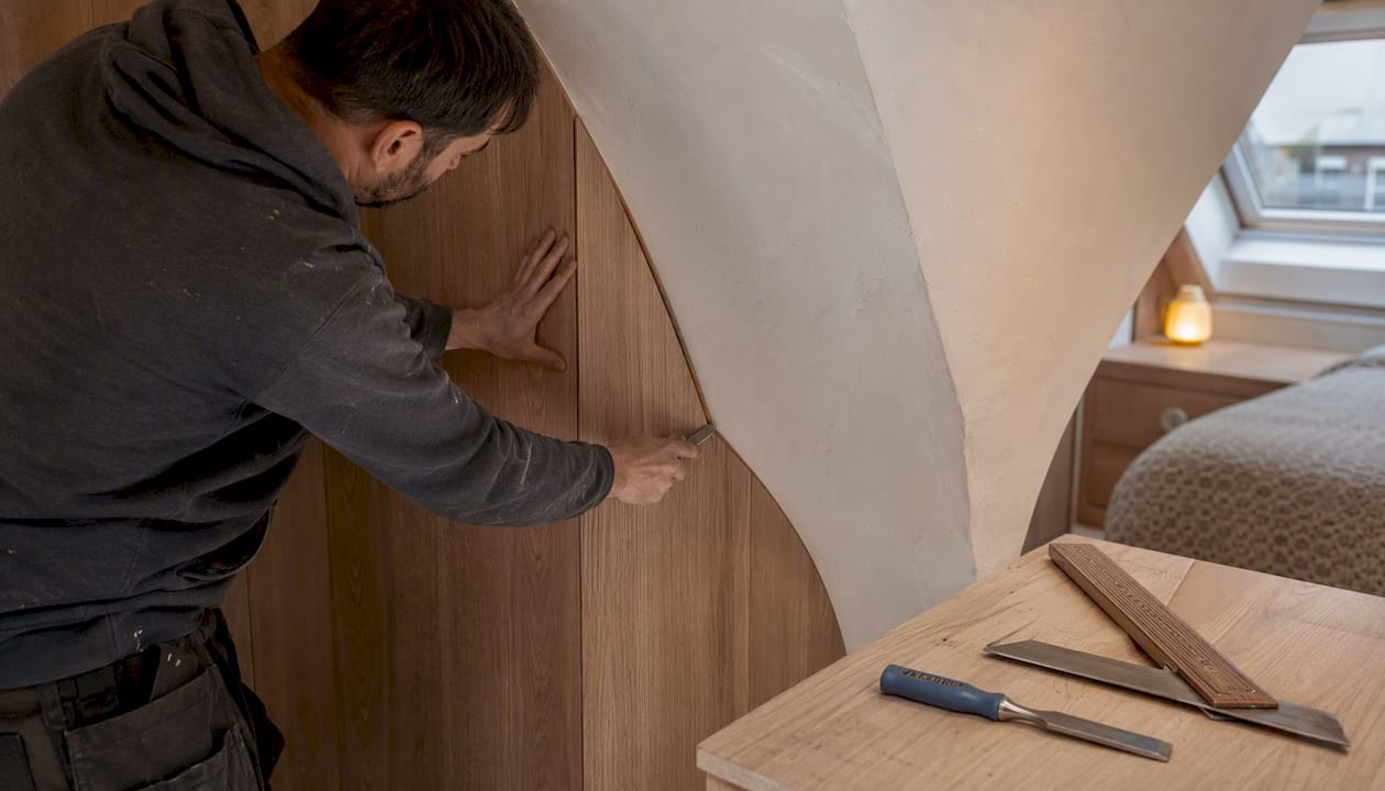 Craftsman fitting scribed wardrobe panel in London loft